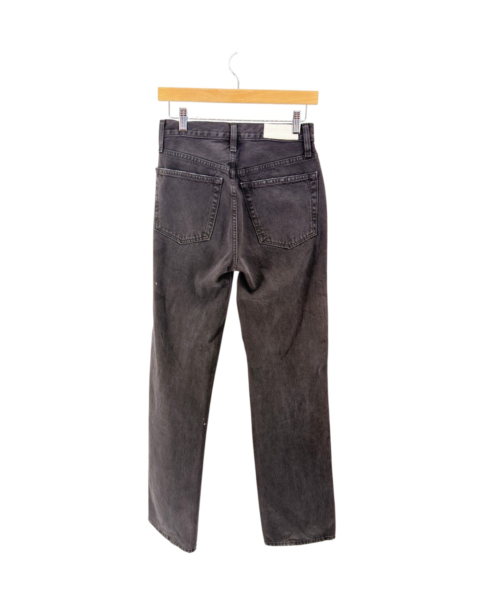 A pair of dark gray washed denim jeans shown from the back, hanging from a light wood hanger against a plain white background.