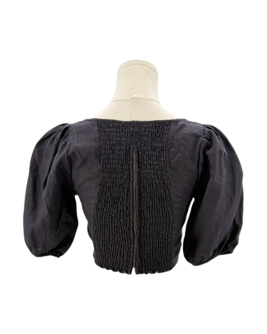 Reformation black blouse with puffed sleeves on a mannequin against a white background