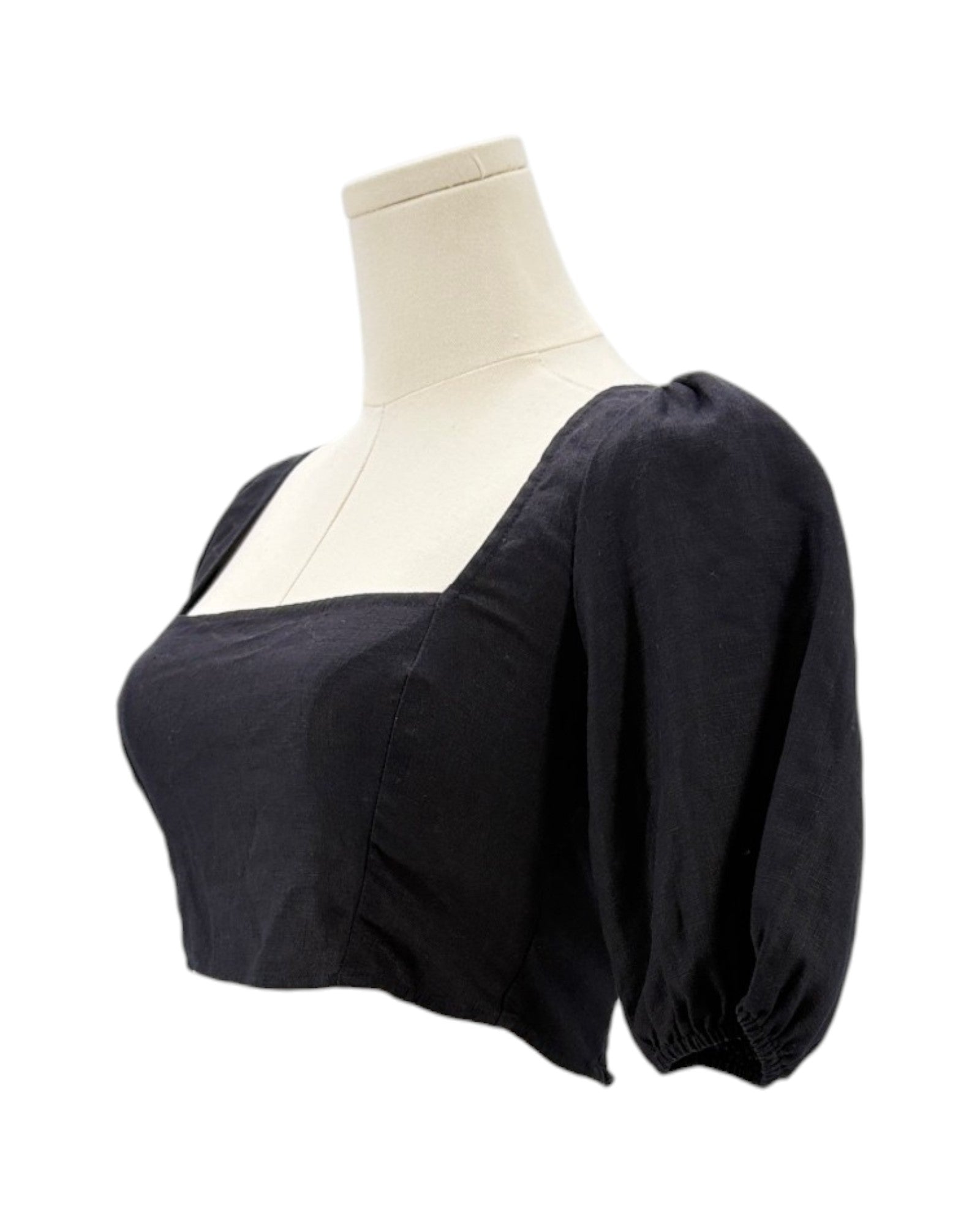 Reformation black blouse with puffed sleeves on a mannequin against a white background