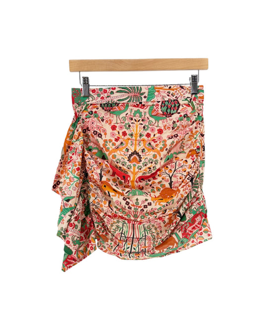 Patterned women's mini skirt with ruffle, featuring a vibrant, multicolored animal and floral print on a cream background, set against a plain white studio backdrop. white background