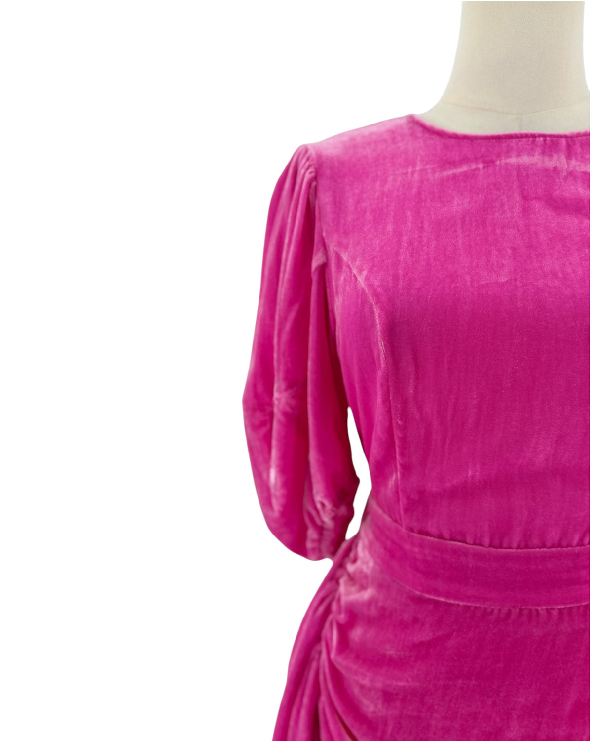 A close-up of a bright magenta pink velvet dress on a mannequin, showing the back of the neck, three-quarter puffed sleeves, and a matching fabric belt at the waist against a plain white background.