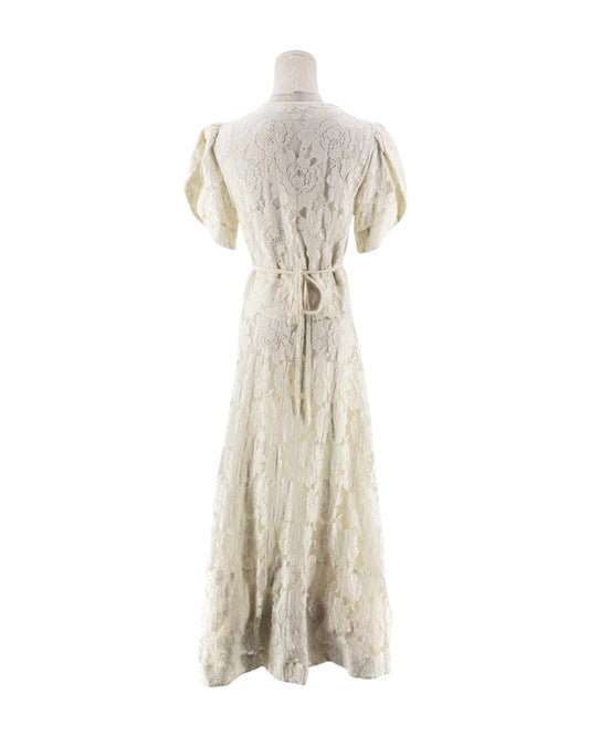 An off-white lace maxi dress with short puff sleeves, a deep V-neckline, and a lace-up front bodice, displayed on a mannequin against a white background.