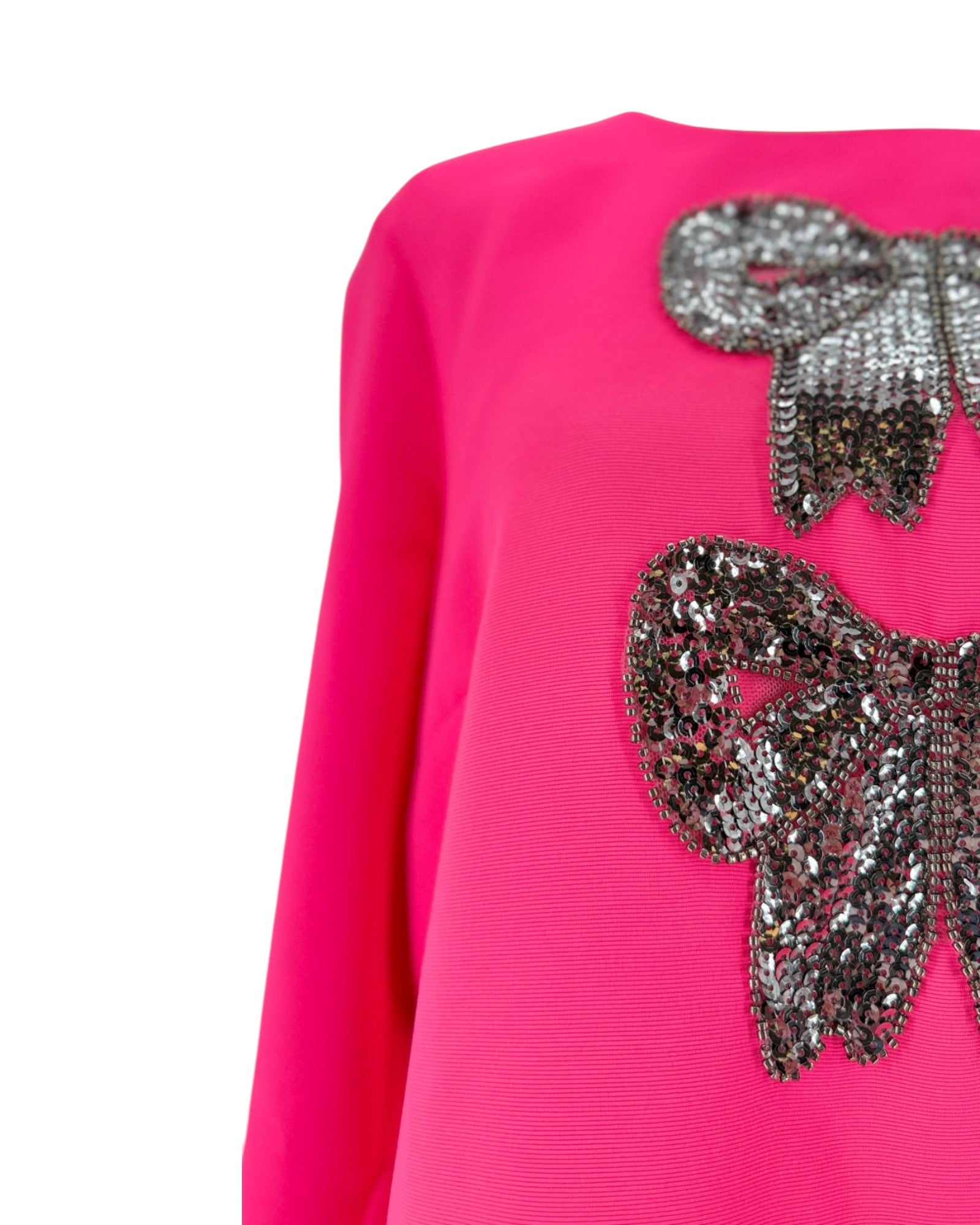 Bright pink long-sleeve top with large sequined bow embellishments on the chest, shown against a plain white background.