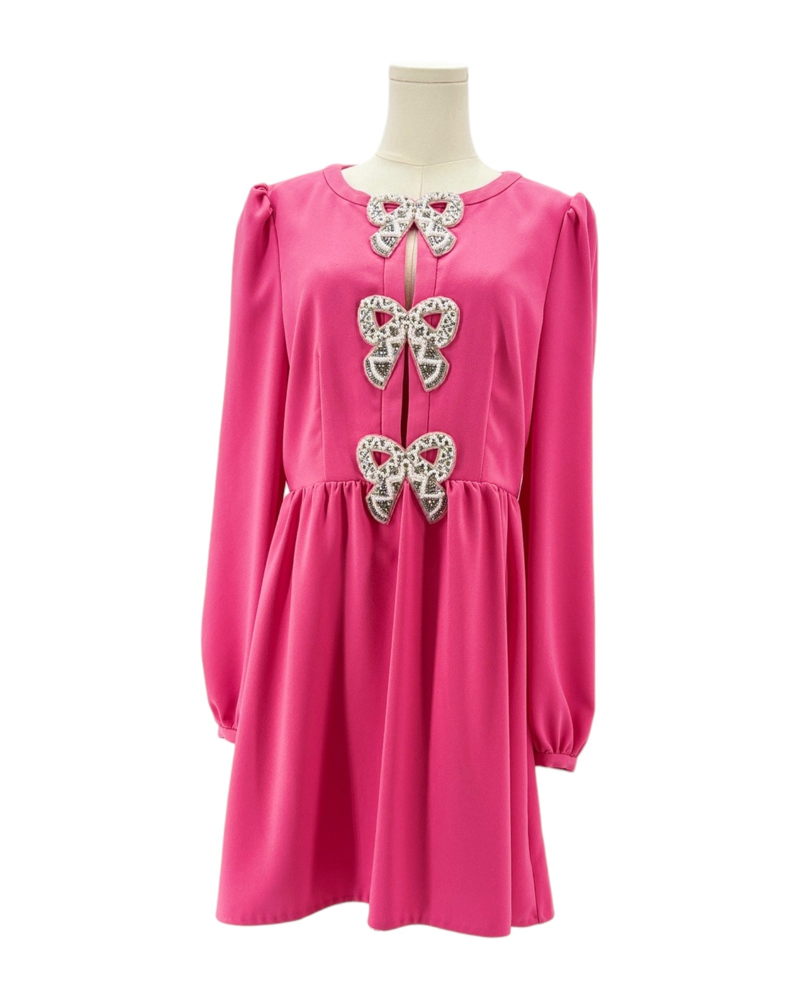 Pink dress with bow embellishments on a mannequin against a white background