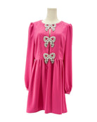Pink dress with bow embellishments on a mannequin against a white background