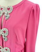 Close-up of a pink garment with decorative bow details on a white background