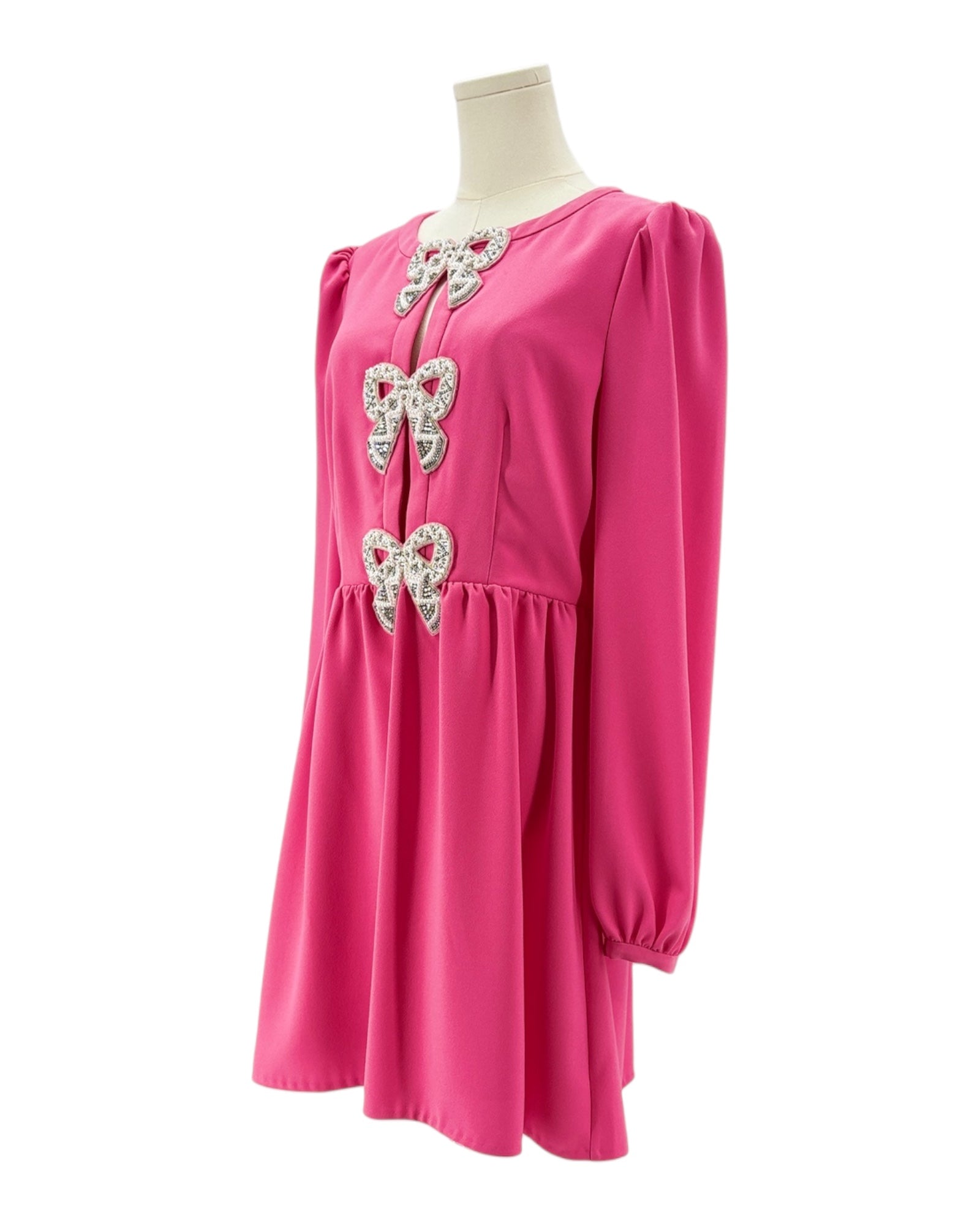 Pink dress with bow embellishments on a mannequin against a white background