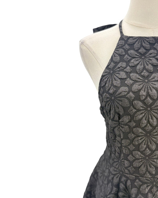 Black floral patterned apron on a mannequin against a white background