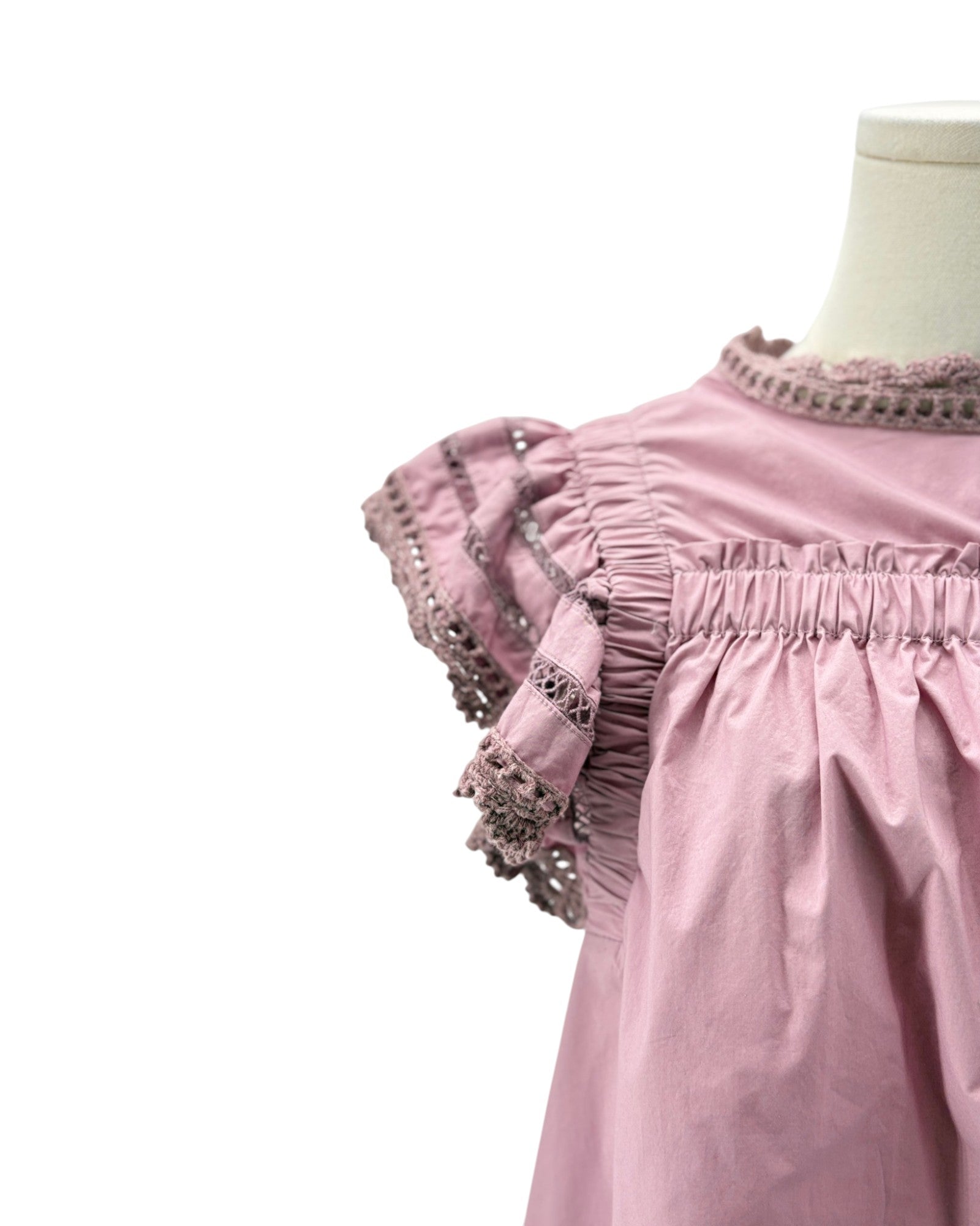 Pink dress with lace details on a mannequin against a white background