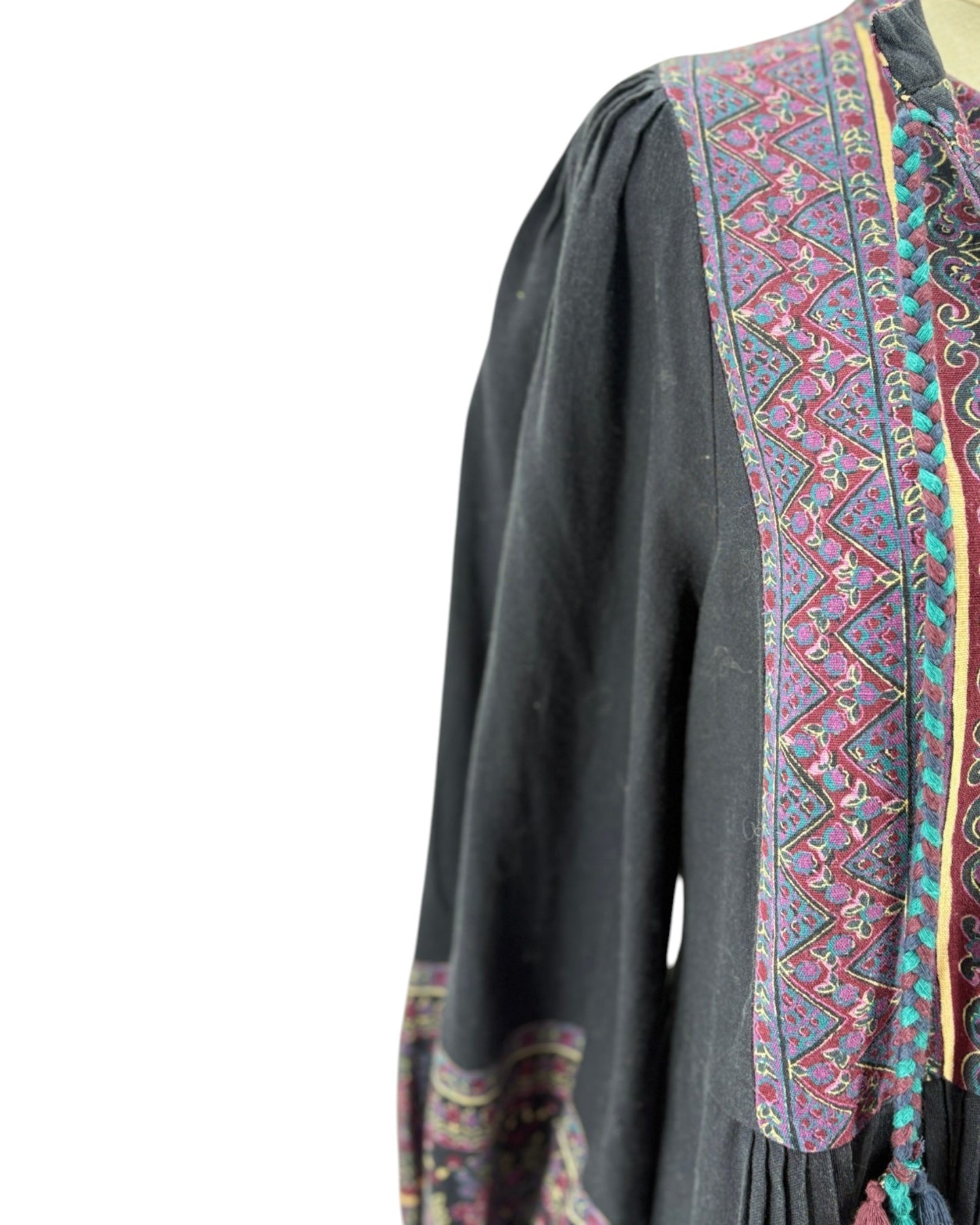 Black long-sleeve top with colorful embroidered patterns on a white background