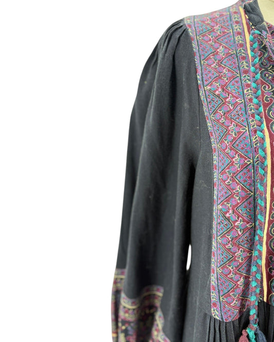 Black long-sleeve top with colorful embroidered patterns on a white background