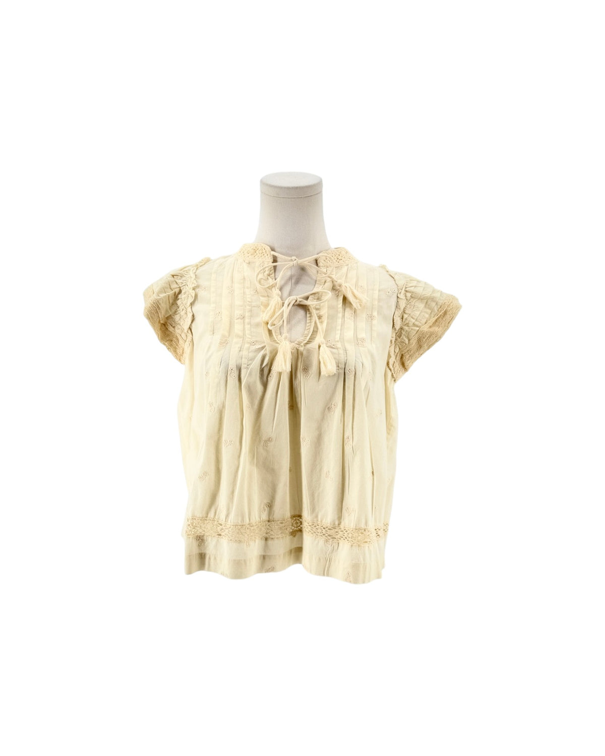Cream short flutter sleeve blouse with tassel and embroidery details on a mannequin on a white background