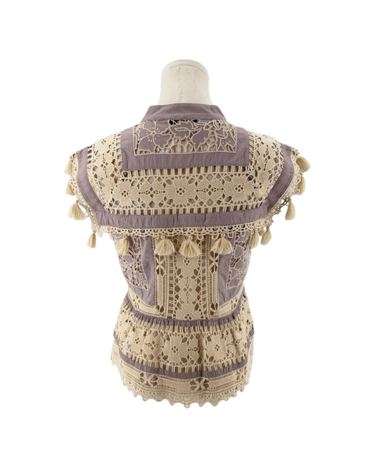 A sleeveless bohemian-style blouse with intricate crochet lace, tassel trim, and embroidery, shown from the back on a mannequin against a white background.