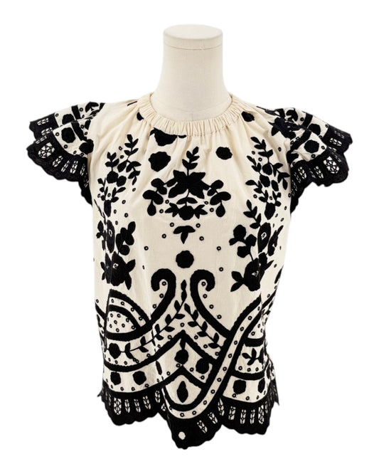 Cream with black applique throughout, flutter sleeves, scalloped hemline, elastic neckline on a white background on a mannequin