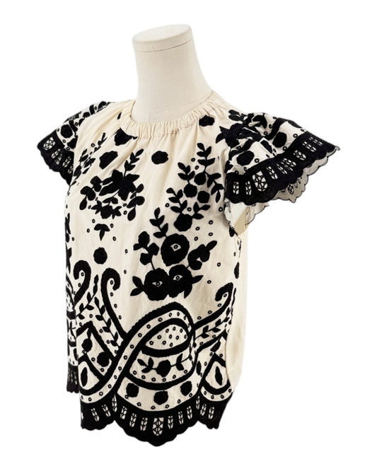 Cream with black applique throughout, flutter sleeves, scalloped hemline, elastic neckline on a white background on a mannequin