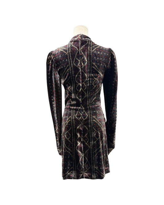 A long-sleeve velvet mini dress shown from the back on a mannequin, featuring a dark base with intricate geometric patterns in gold, red, and blue.