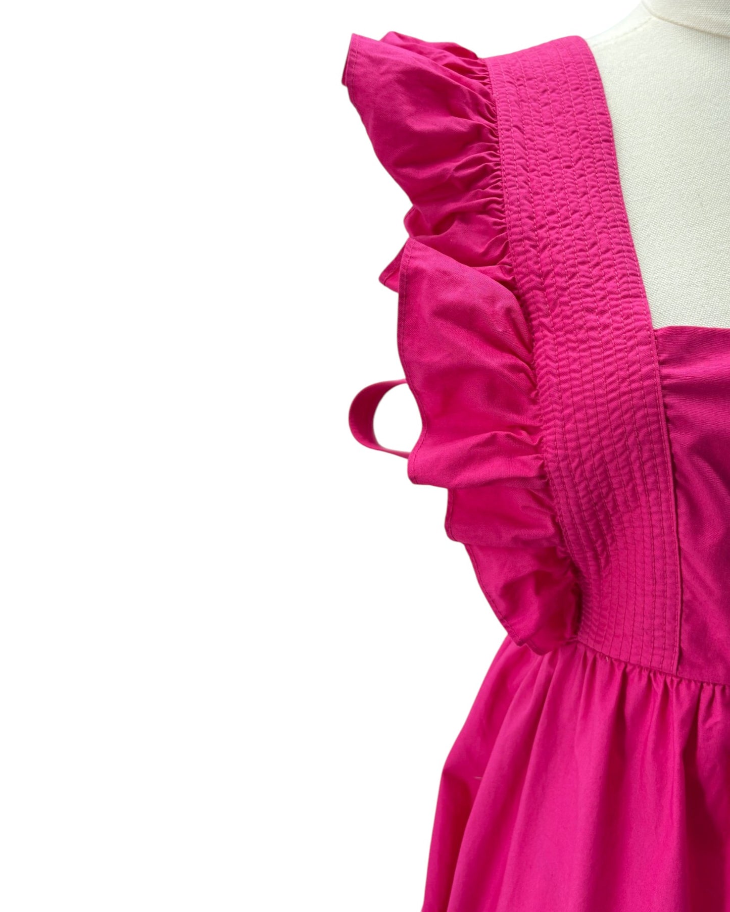 Close-up of a bright pink dress with ruffled details on a white background