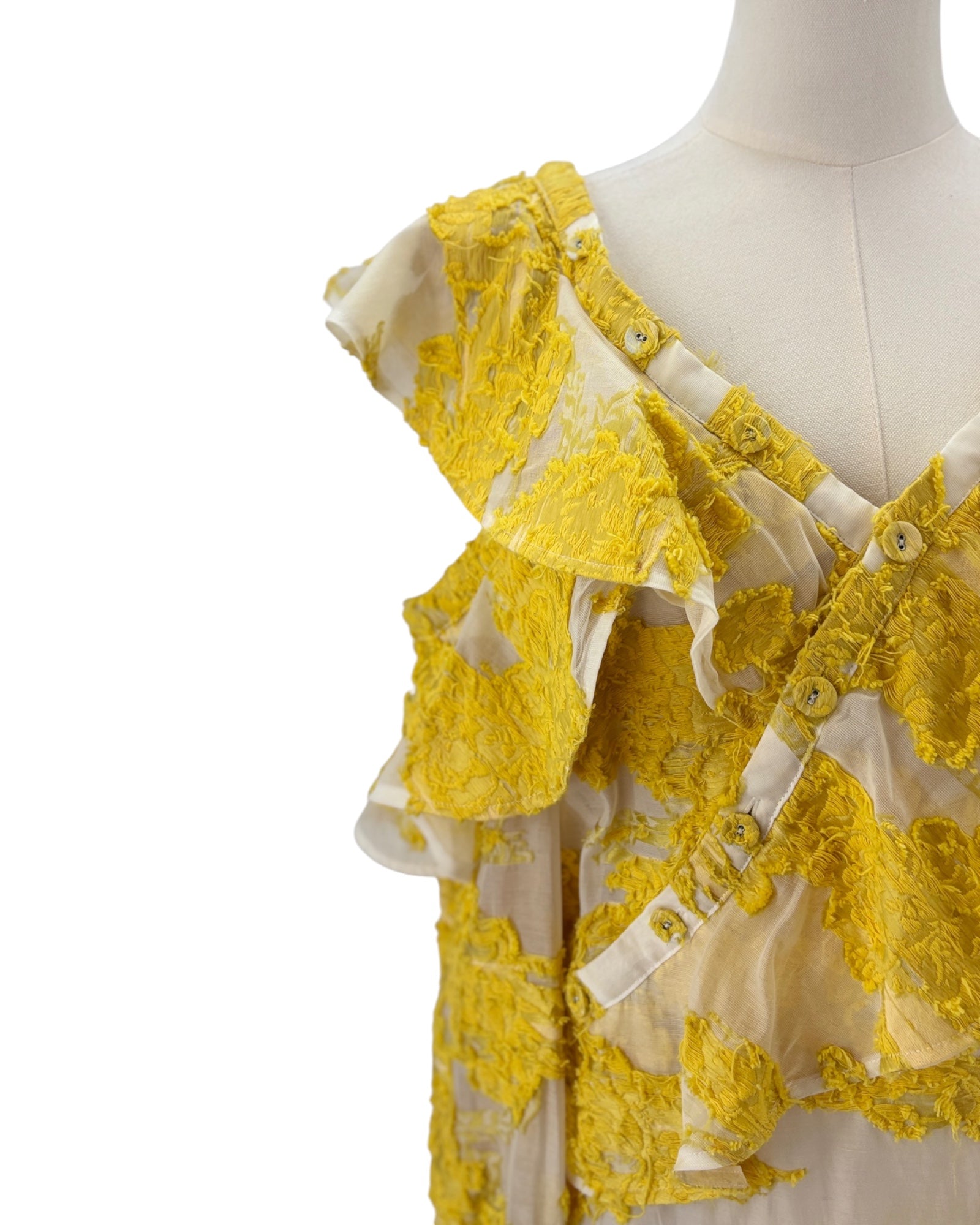 Yellow lace top on a mannequin against a white background
