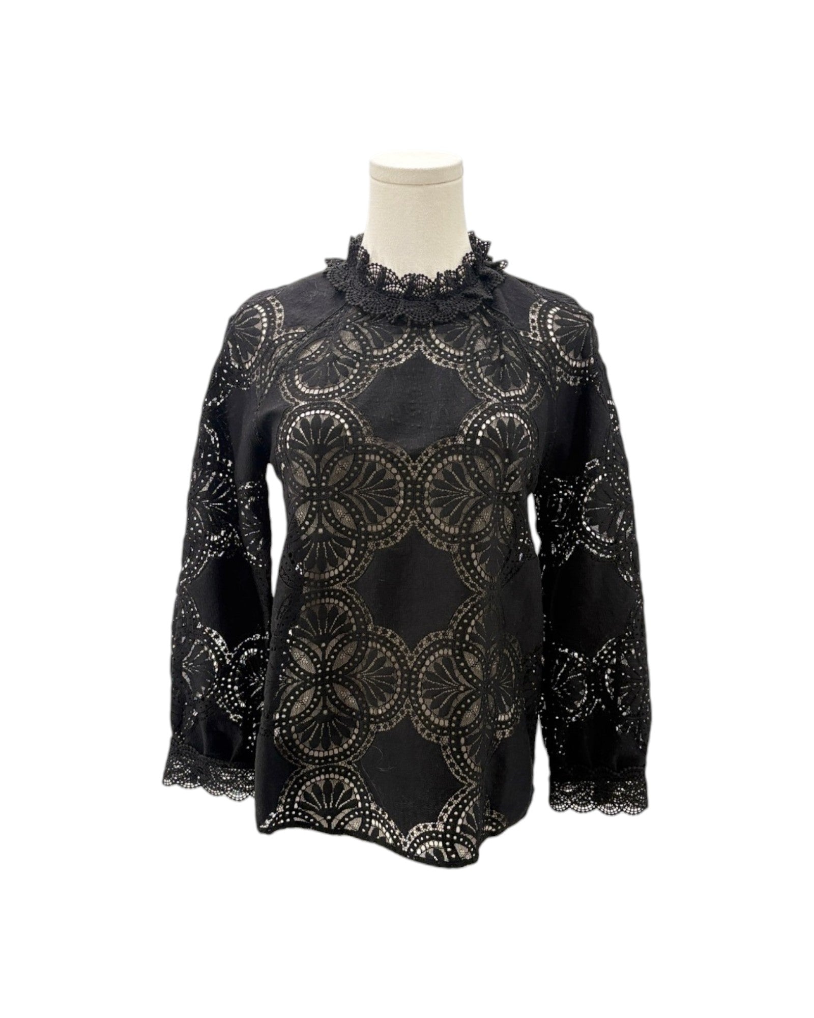 A black long-sleeve blouse with an intricate circular lace overlay pattern, displayed on a mannequin torso against a plain white background.