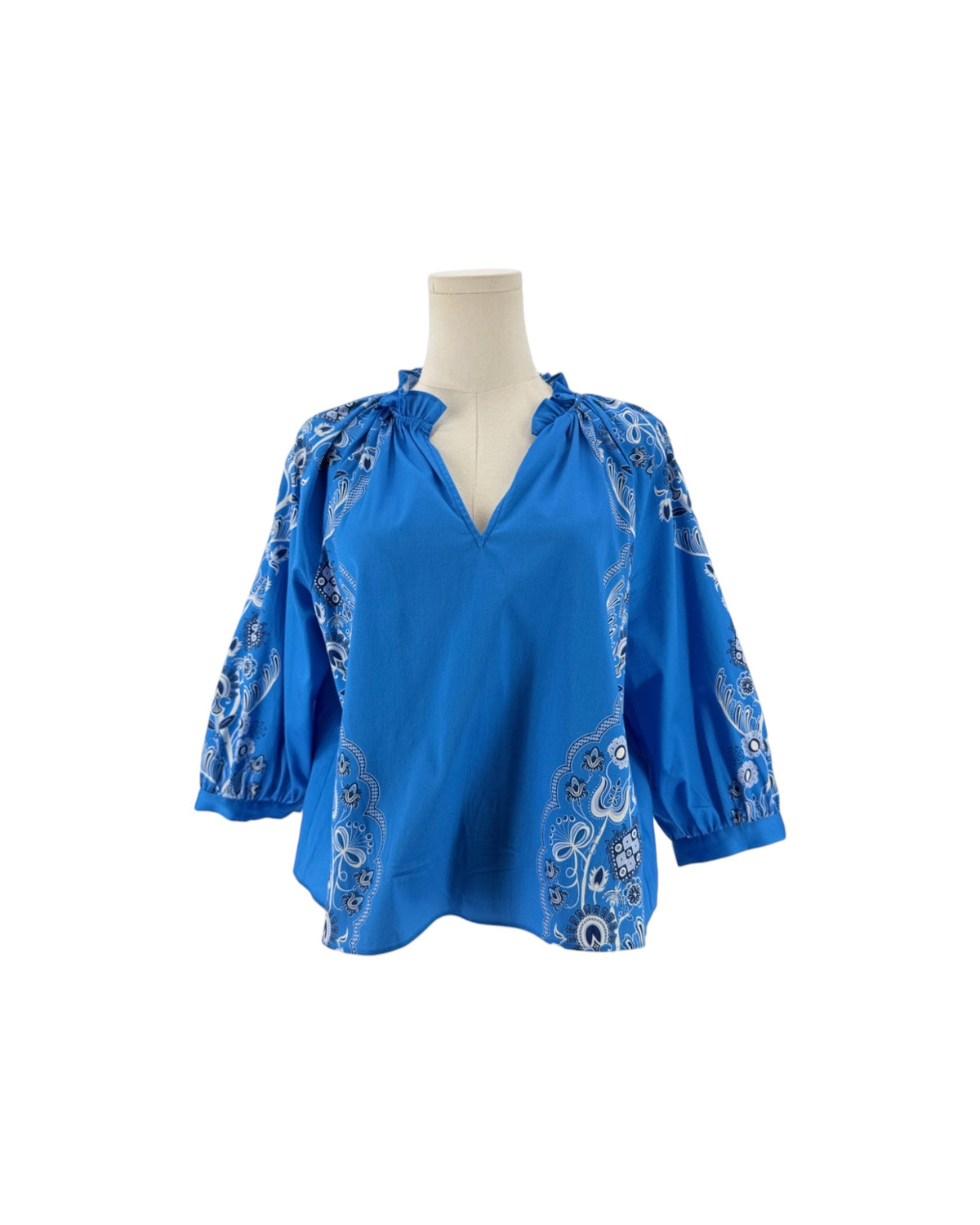 Long sleeve bright blue blouse with a white and black print resembling a bandana on a mannequin on a white background