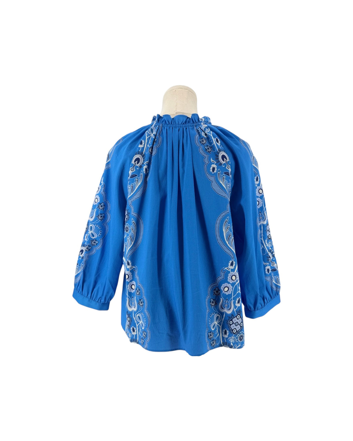Long sleeve bright blue blouse with a white and black print resembling a bandana on a mannequin on a white background
