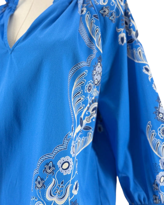 Long sleeve bright blue blouse with a white and black print resembling a bandana on a mannequin on a white background