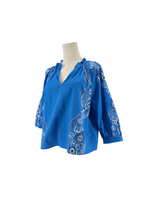 Long sleeve bright blue blouse with a white and black print resembling a bandana on a mannequin on a white background