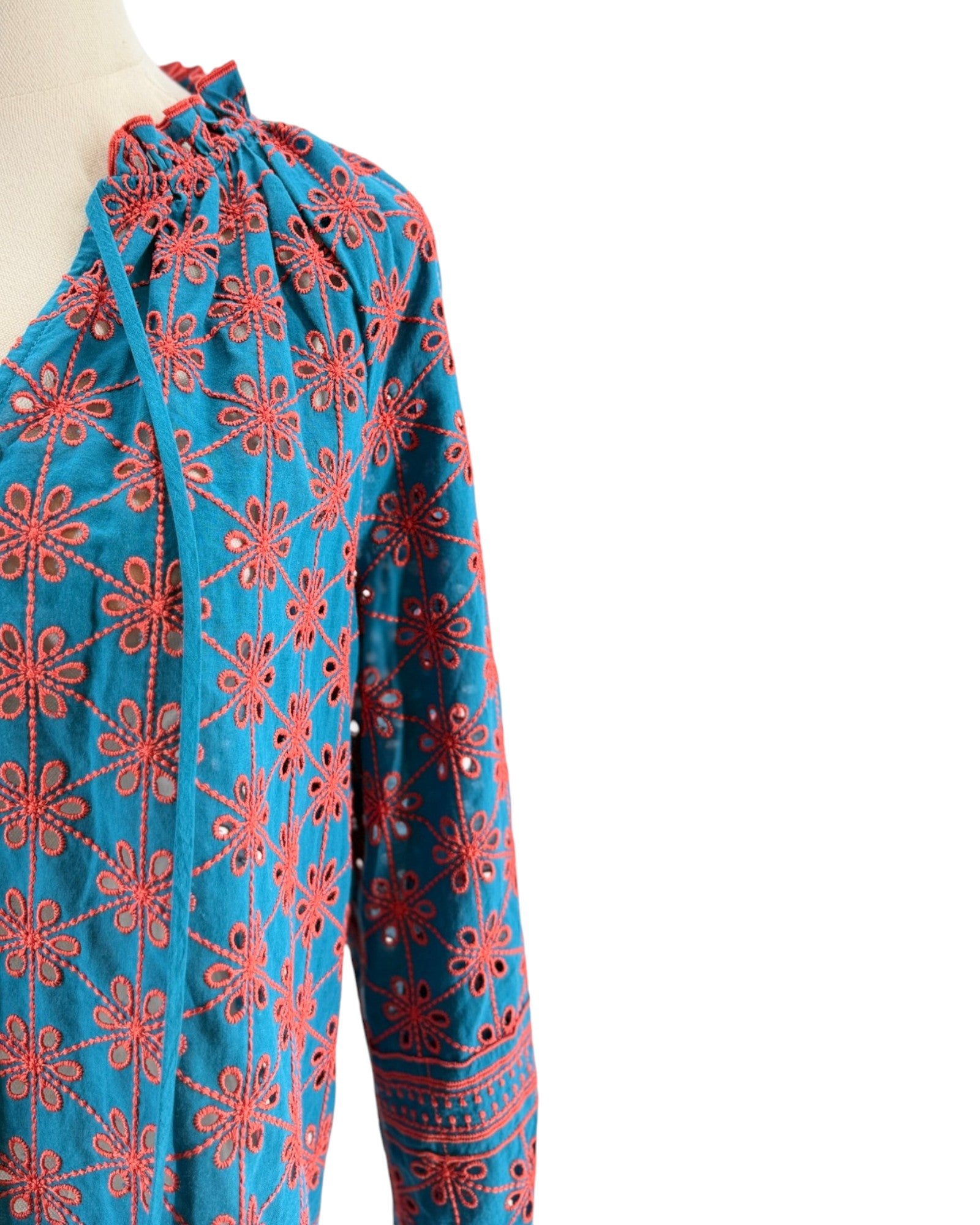 Blue and red embroidered garment on a mannequin with a white background