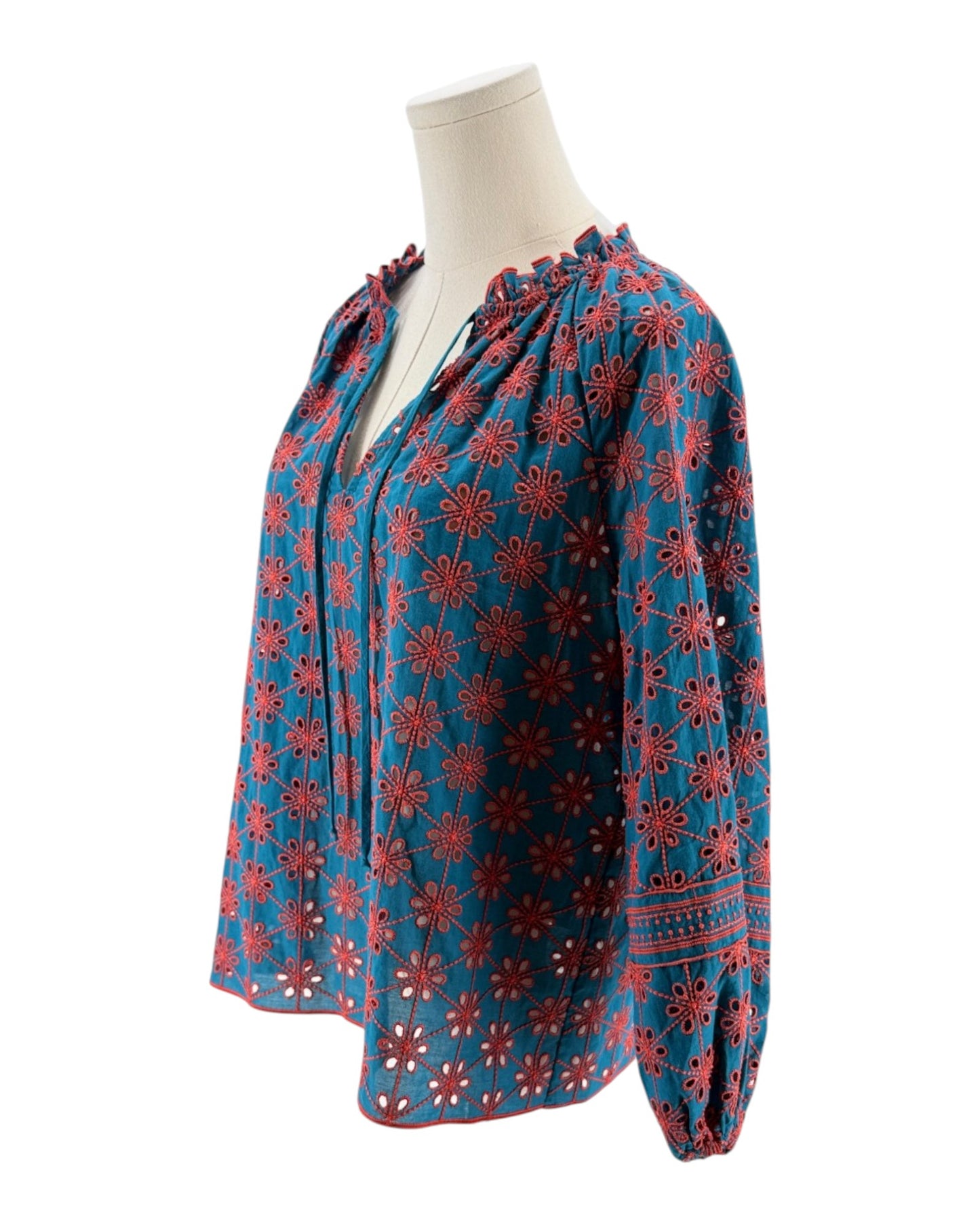 Blue blouse with red floral pattern on a mannequin against a white background