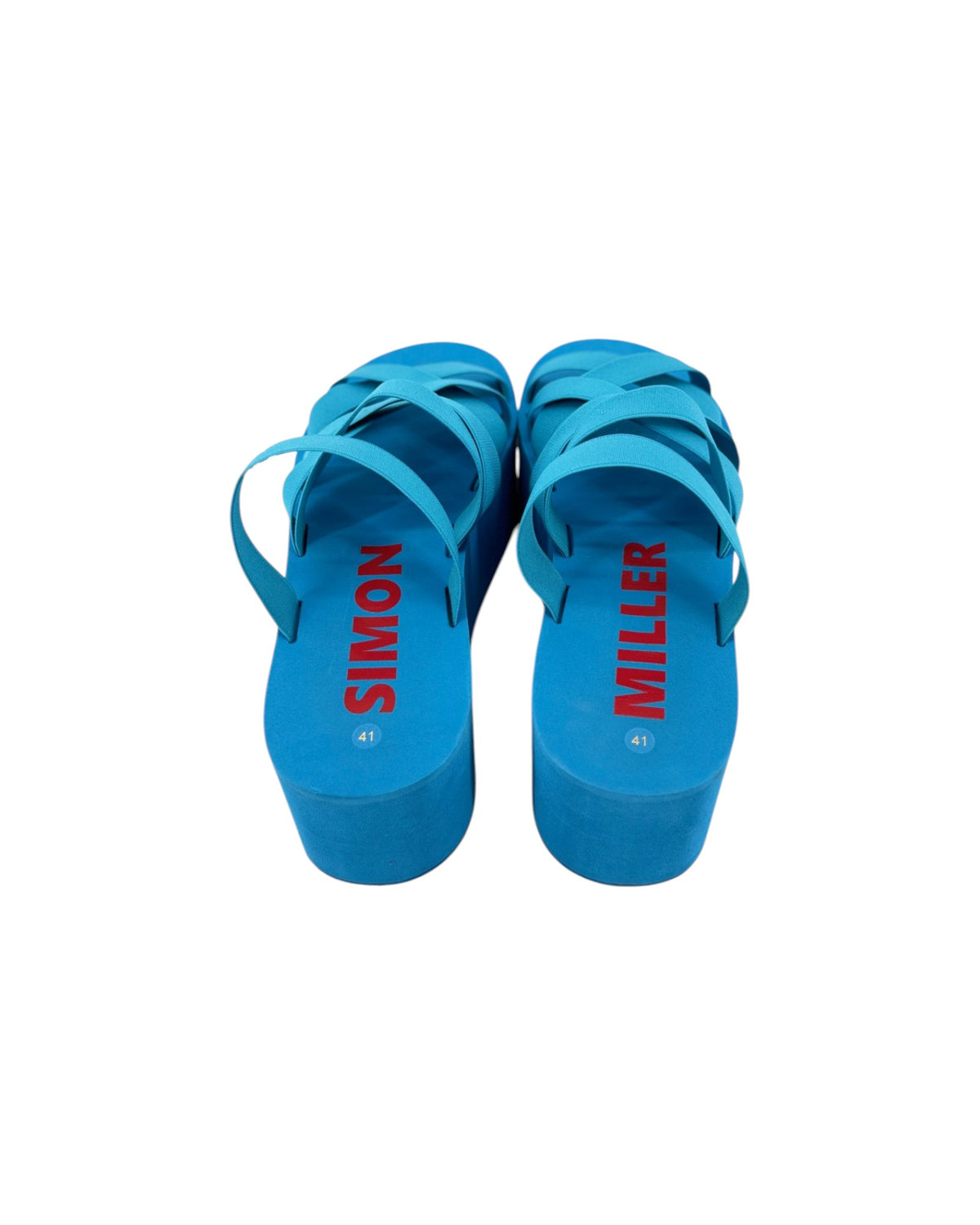 A pair of bright blue platform sandals with multiple crisscrossing straps, shown from the back on a plain white background. The brand names 'SIMON' and 'MILLER' are printed in red on the insoles.