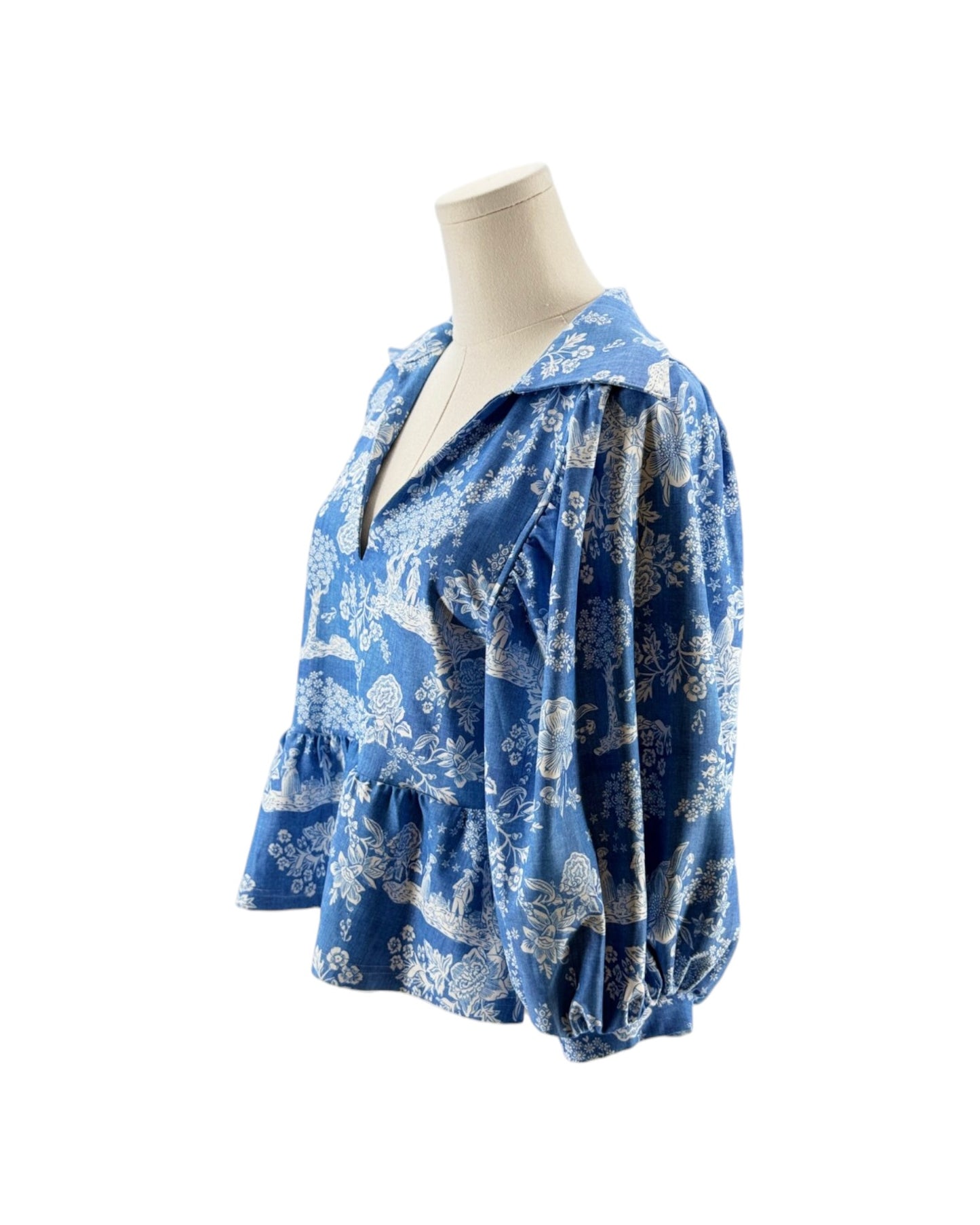 Blue floral blouse on a mannequin against a white background