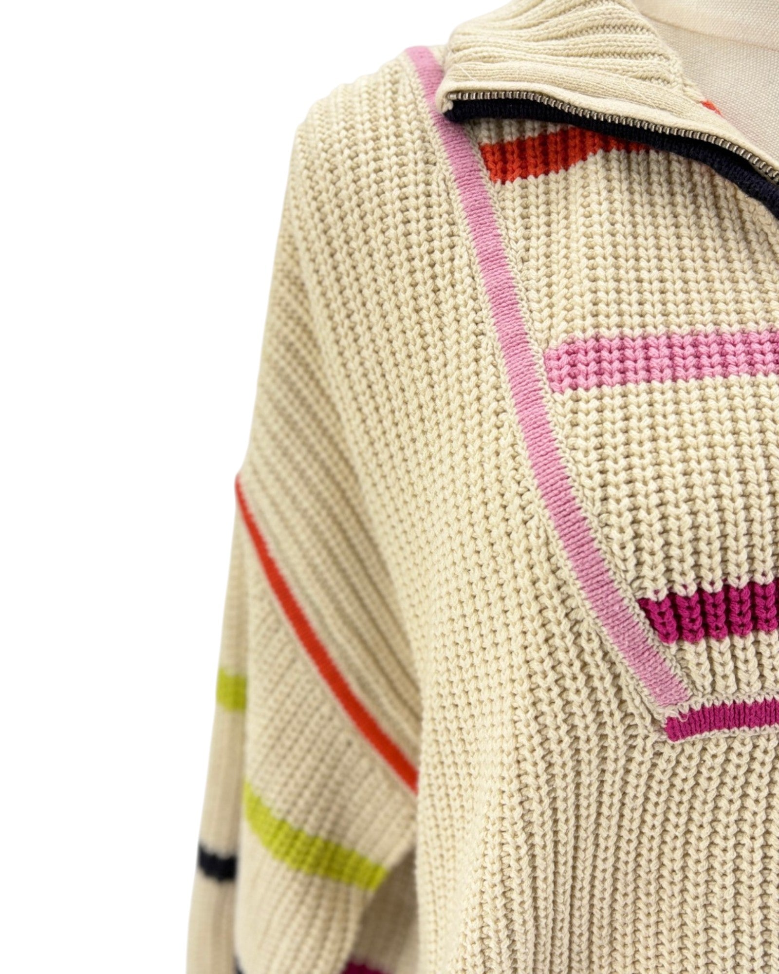Close-up of a chunky knit sweater in cream with colorful striped accents in pink, red, orange, yellow, and black.