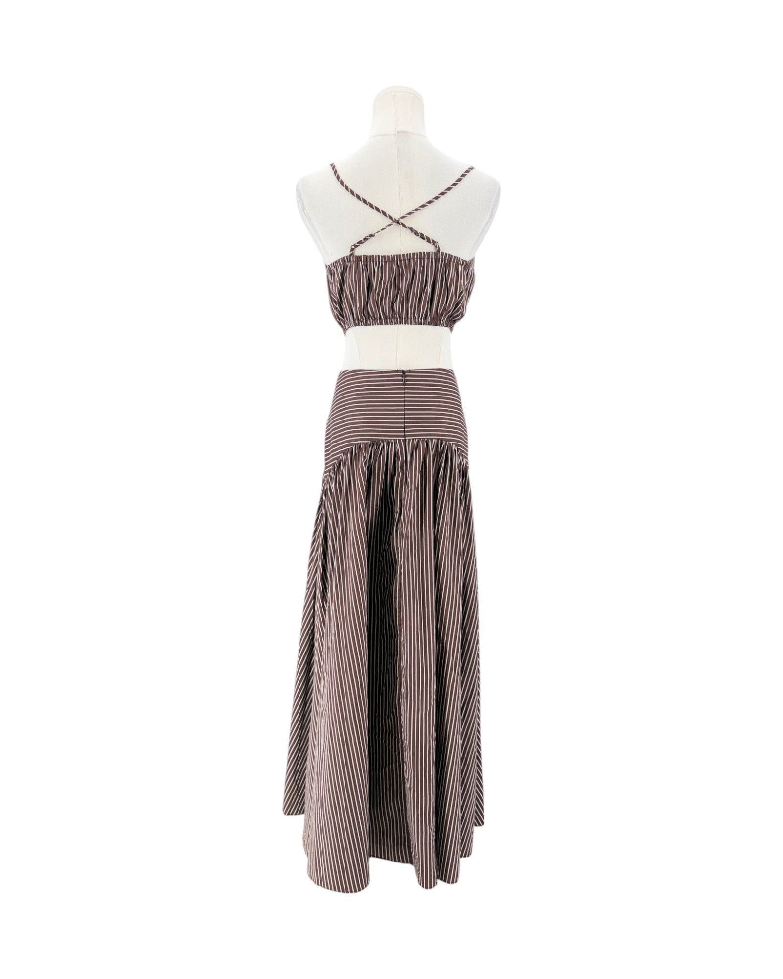 A two-piece two-tone striped maxi dress displayed on a mannequin against a white background. The dress features a brown and white vertically striped crop top with criss-cross straps and a matching high-waisted, gathered maxi skirt.