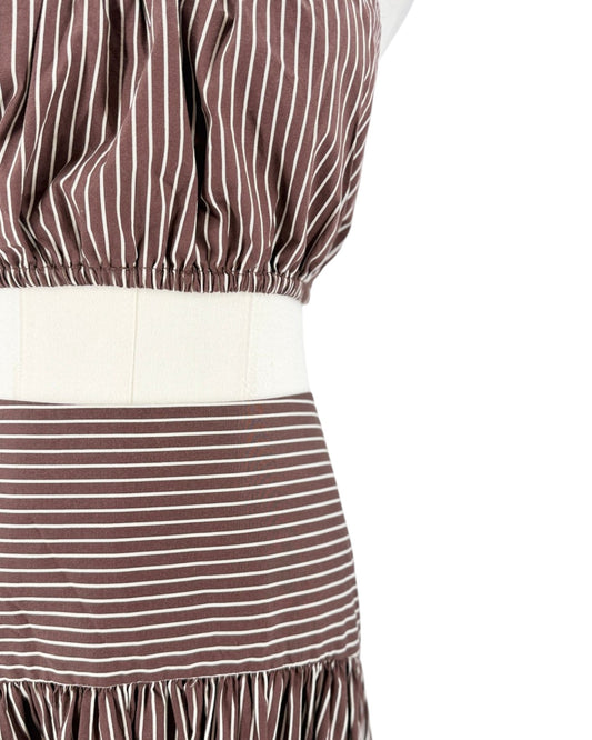 Close-up of a brown and white striped garment on a mannequin, showing a gathered waistband, a wide cream-colored waist panel, and a ruffled hem against a white background.