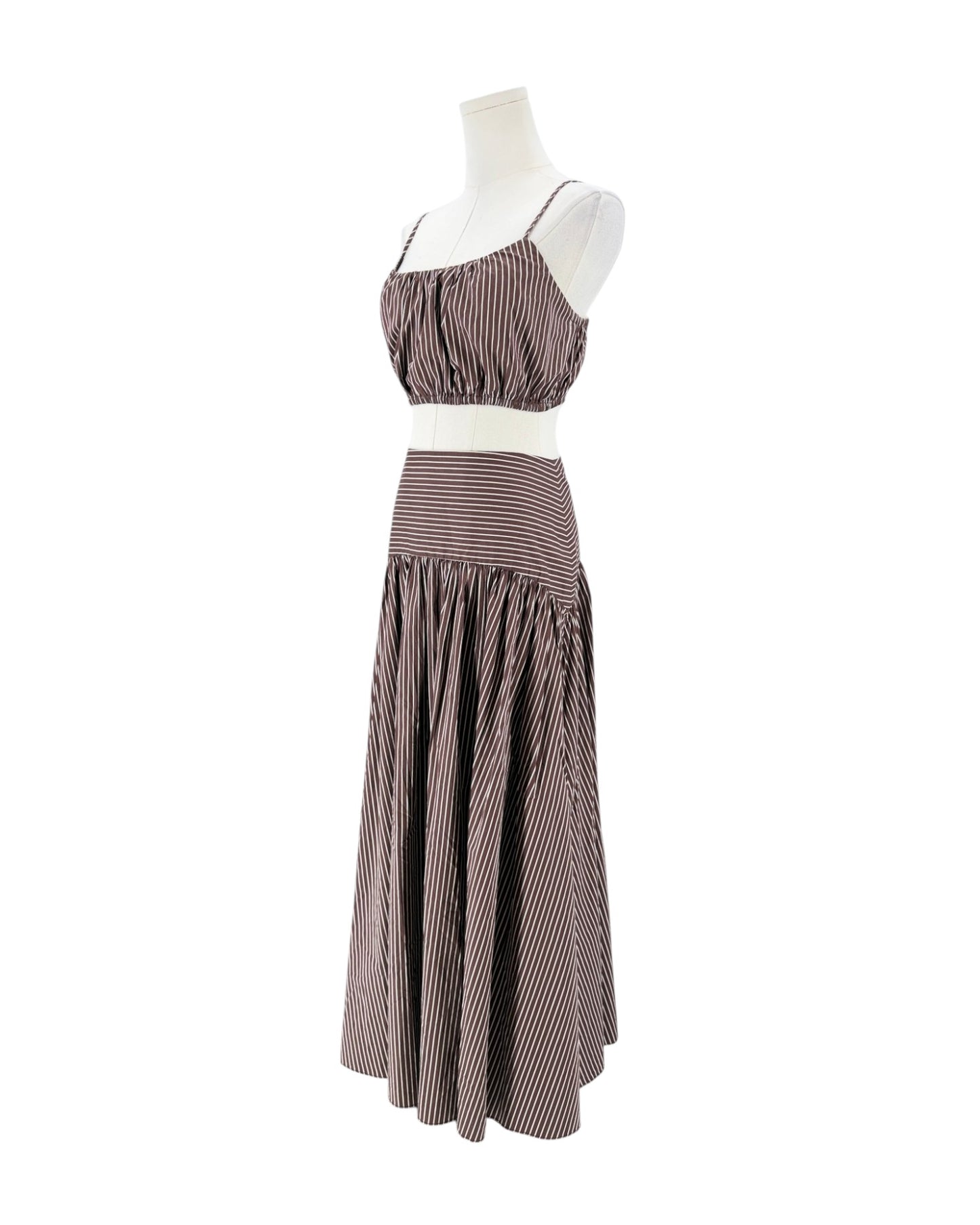 A sleeveless two-piece set consisting of a ruched crop top and a tiered maxi skirt, both in a brown and white striped pattern, displayed on a white mannequin against a white background.