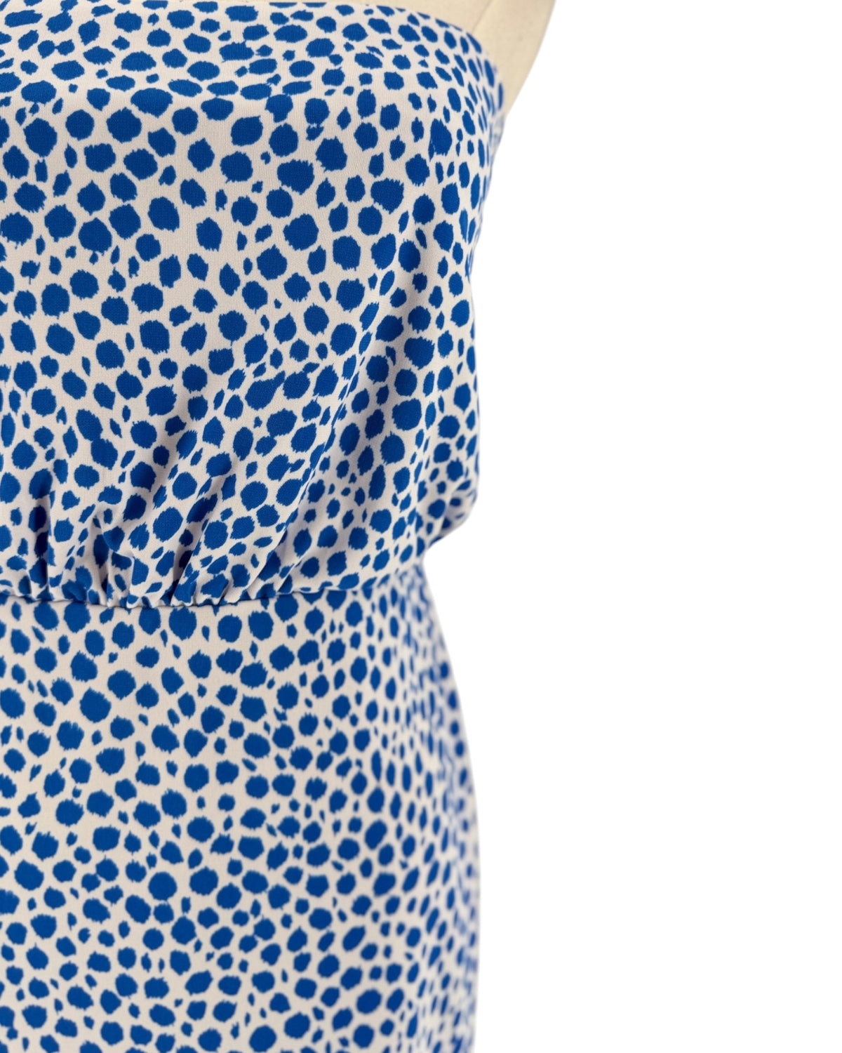 Close-up of a strapless dress with a blue and white spotted pattern, shown on a mannequin against a plain white background.