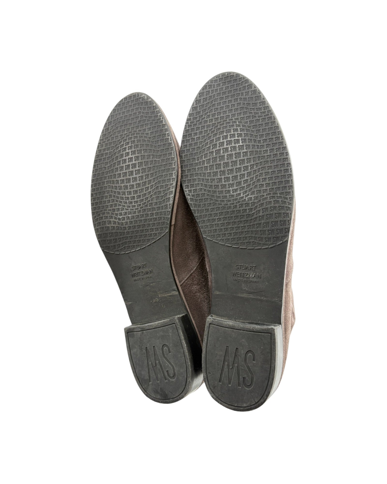 The soles of a pair of brown leather shoes, showing a textured black tread and a brown leather heel counter with an embossed 'MS' logo, photographed against a white background.