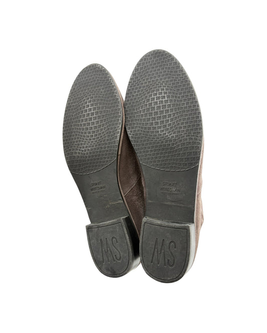 The soles of a pair of brown leather shoes, showing a textured black tread and a brown leather heel counter with an embossed 'MS' logo, photographed against a white background.