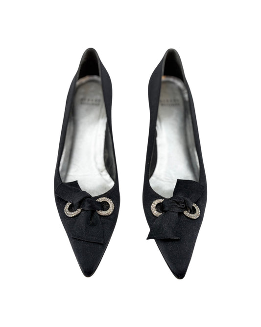 Pair of black high-heeled shoes with bow details on a white background