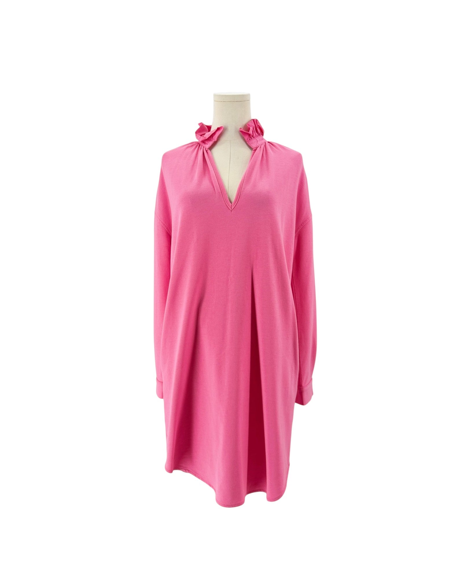 A bright pink long-sleeve tunic dress with a split neckline and bow details, displayed on a mannequin torso against a plain white background.