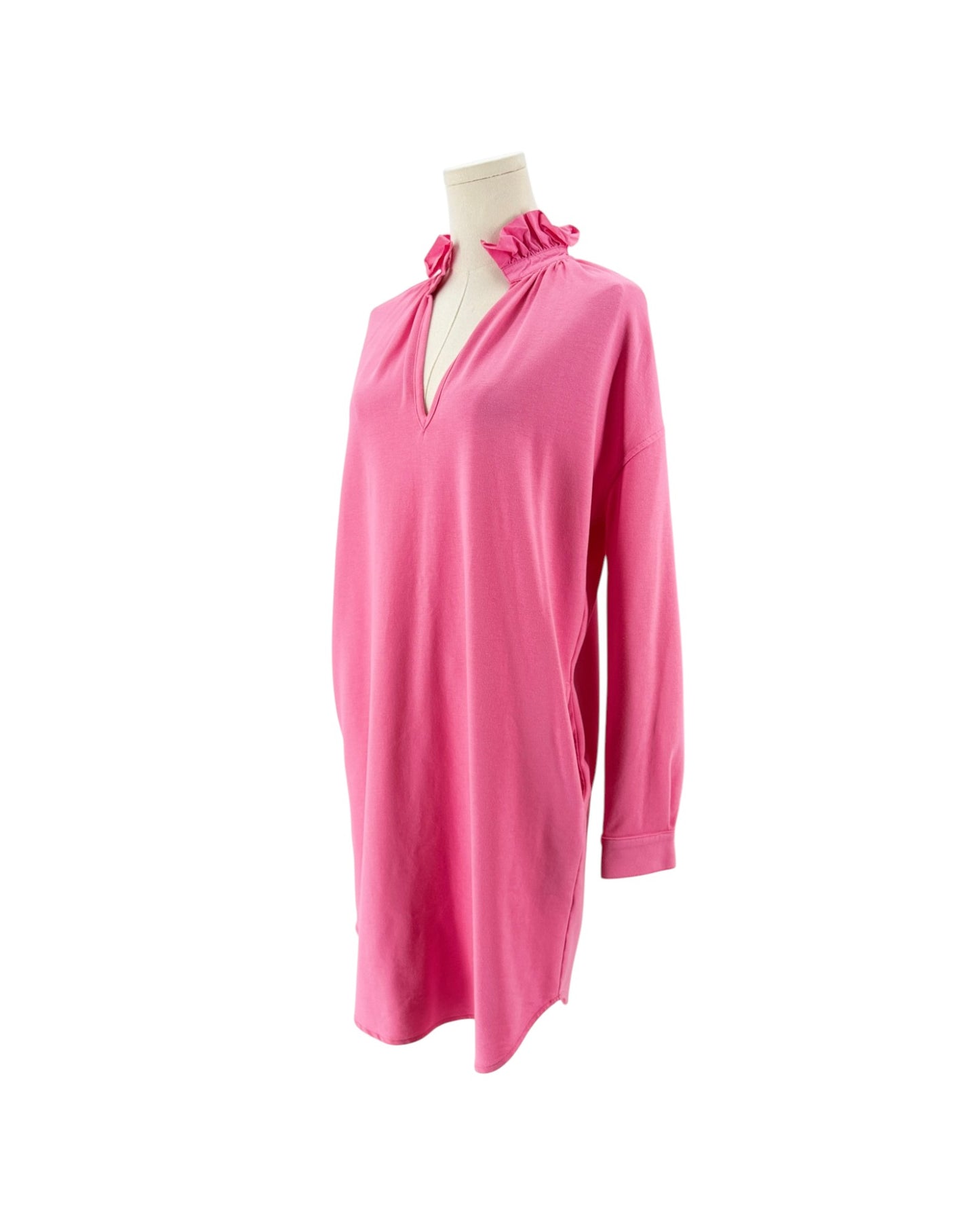 A bright pink long-sleeve tunic dress with a ruffled keyhole neckline, displayed on a cream mannequin torso against a plain white background.