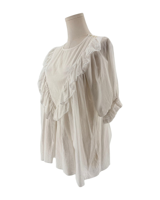 White ruffle triangle top, v-shaped ruffle down the body, voluminous short sleeves, round neckline on a mannequin on a white background
