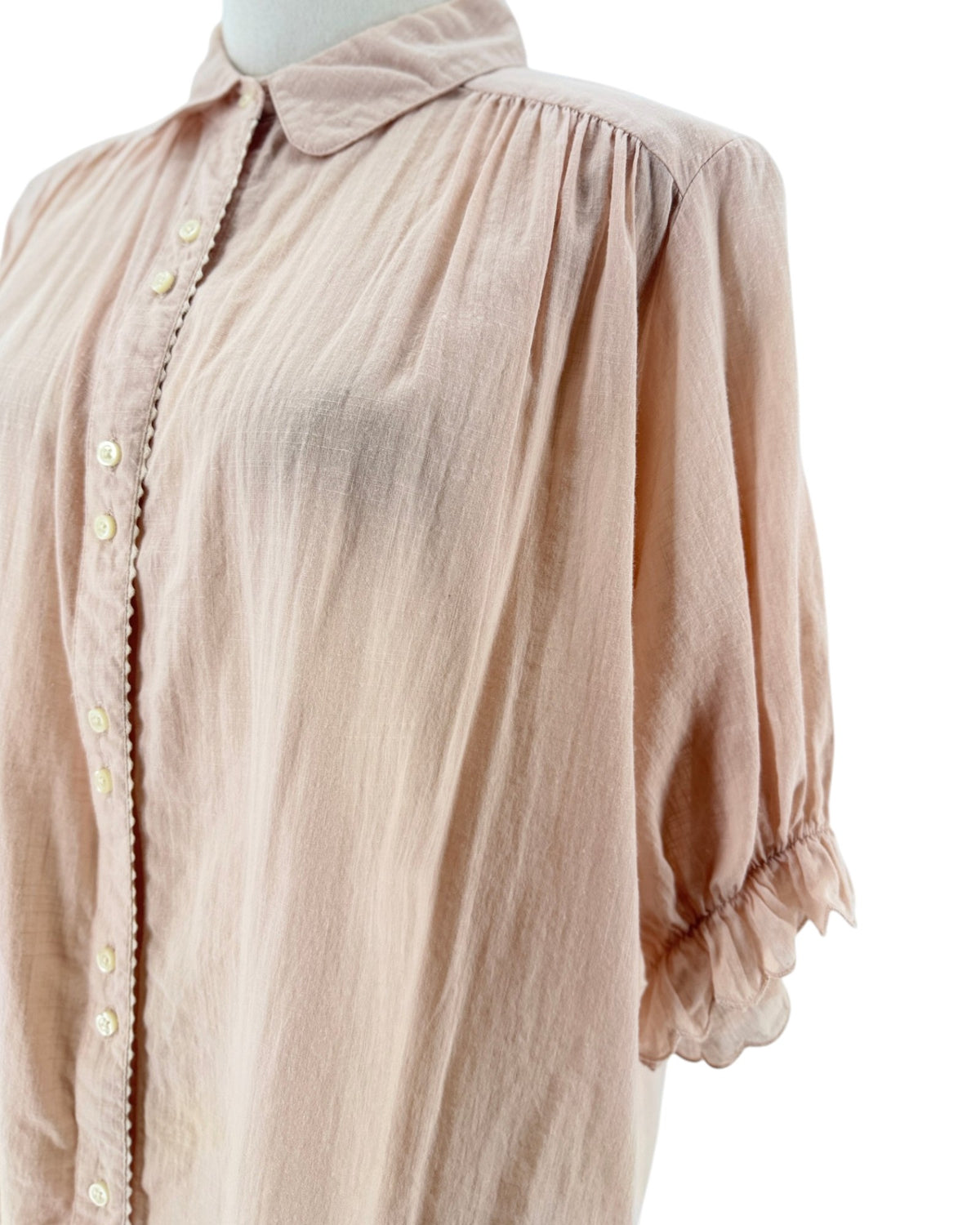 Short sleeve light pink button down top with ruffle details on a mannequin on a white background