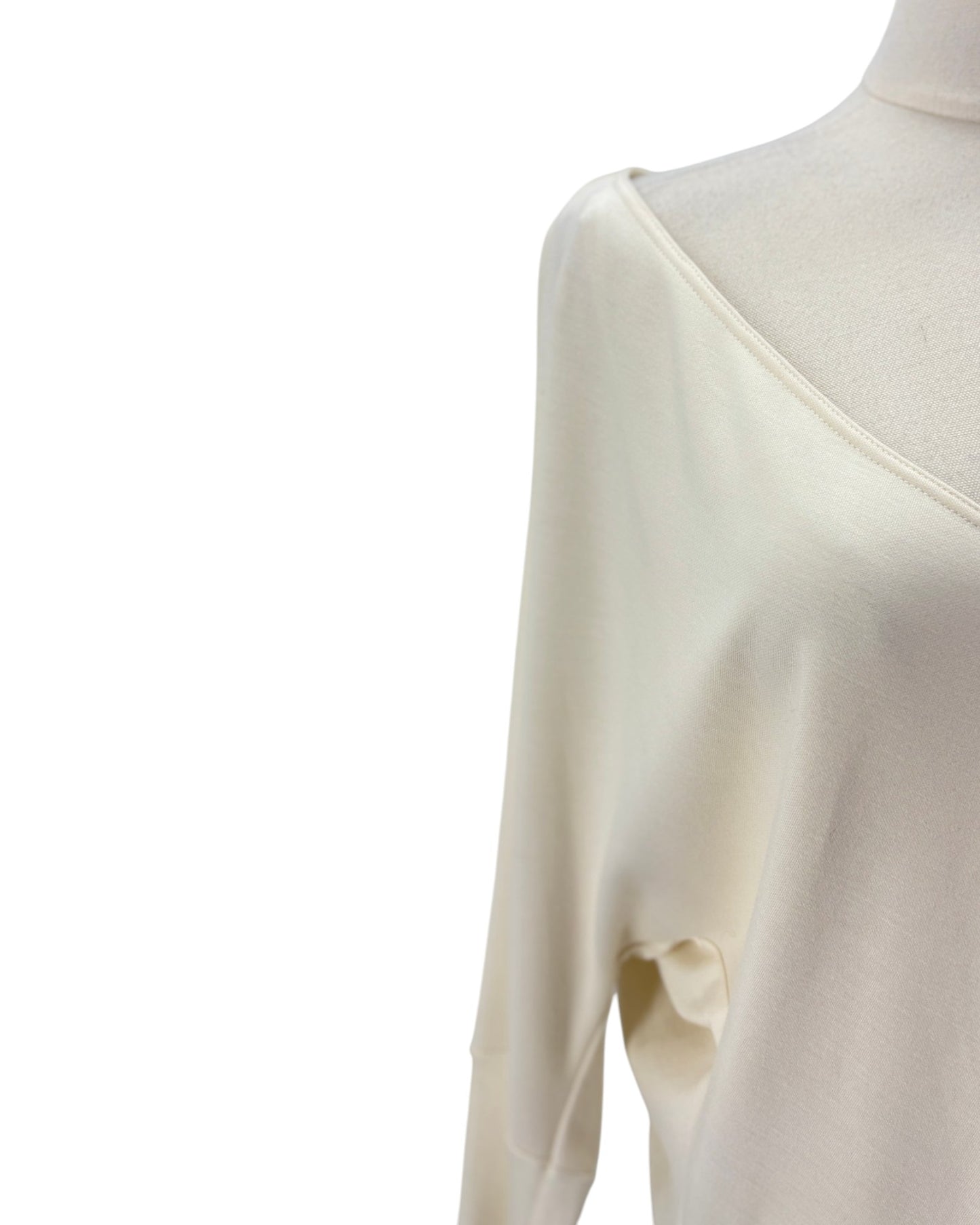 Close-up of a cream-colored long-sleeve top on a mannequin, showing the shoulder and upper chest area against a plain white background.
