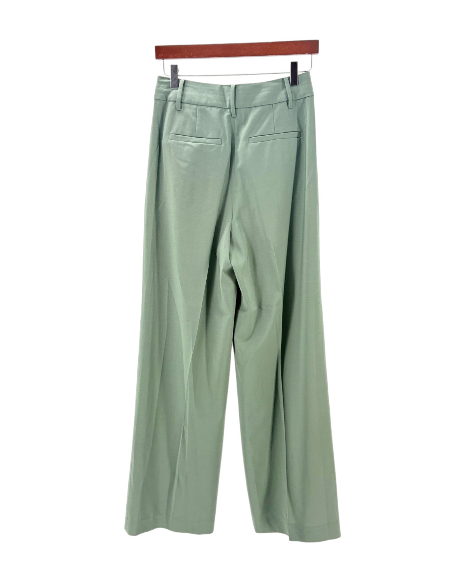 Light green pants on a hanger against a white background