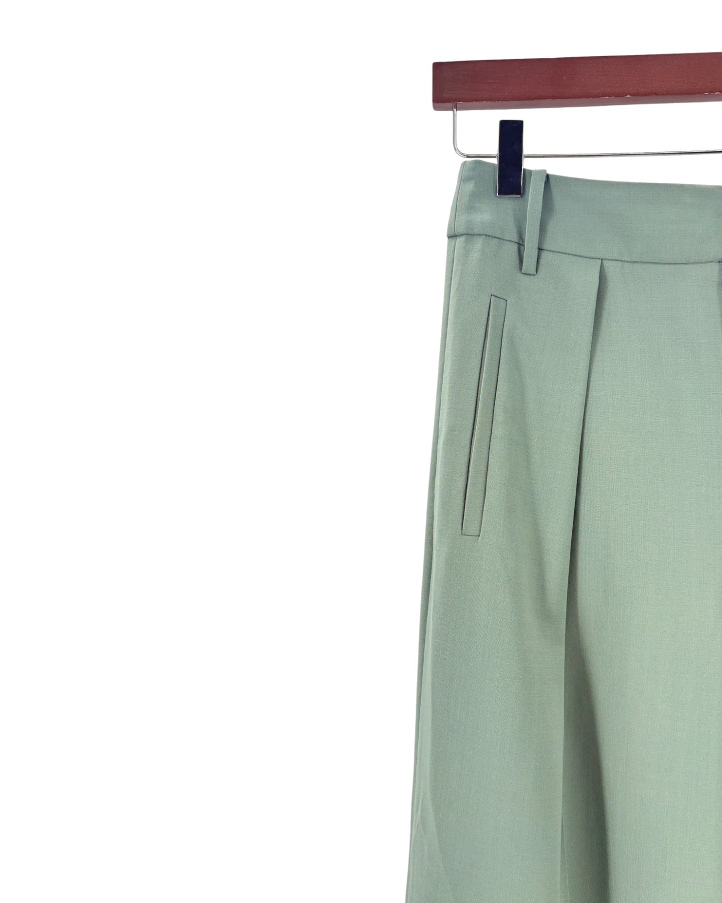 Light green pants hanging on a rack against a white background