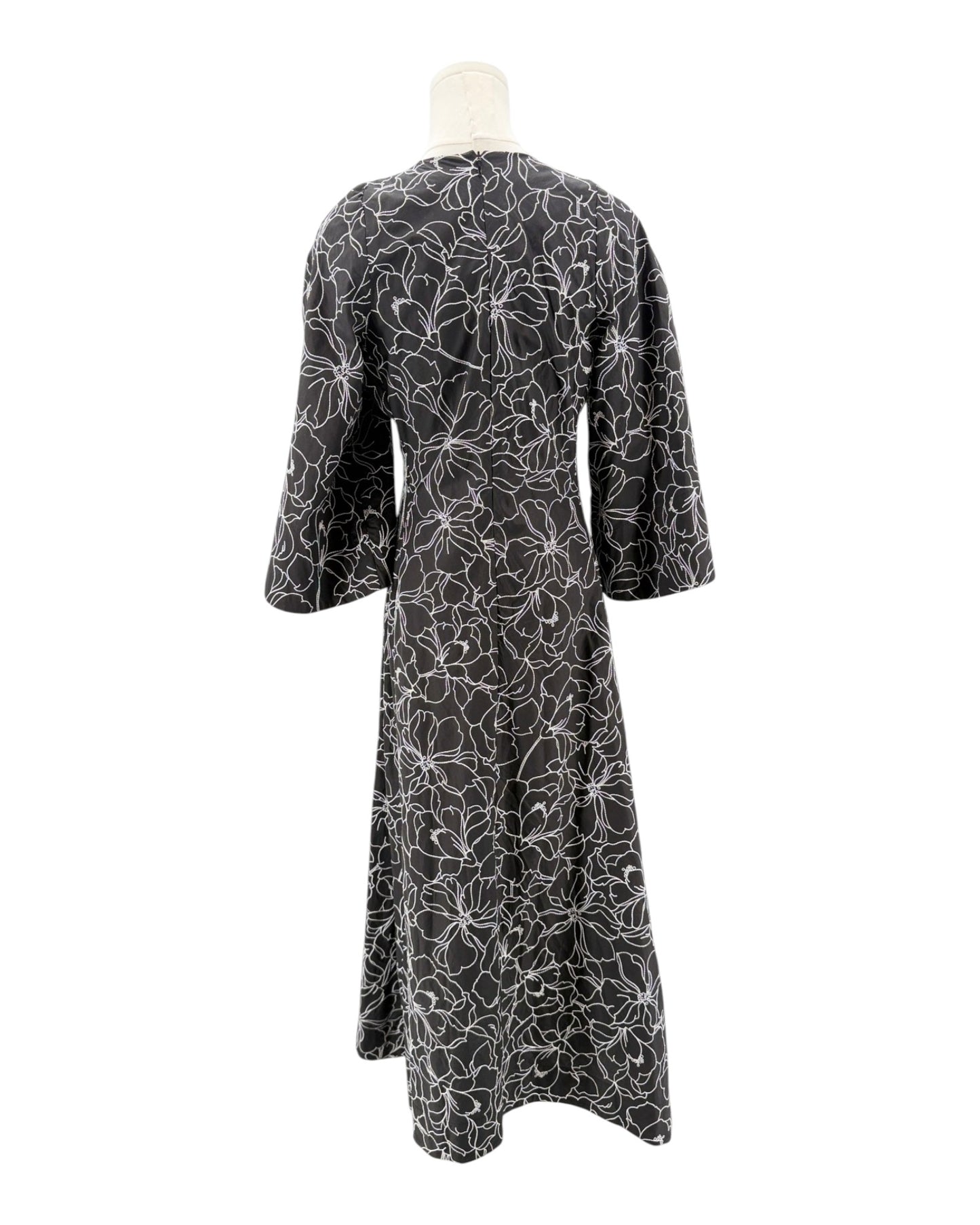 Black dress with white floral pattern on a mannequin against a white background