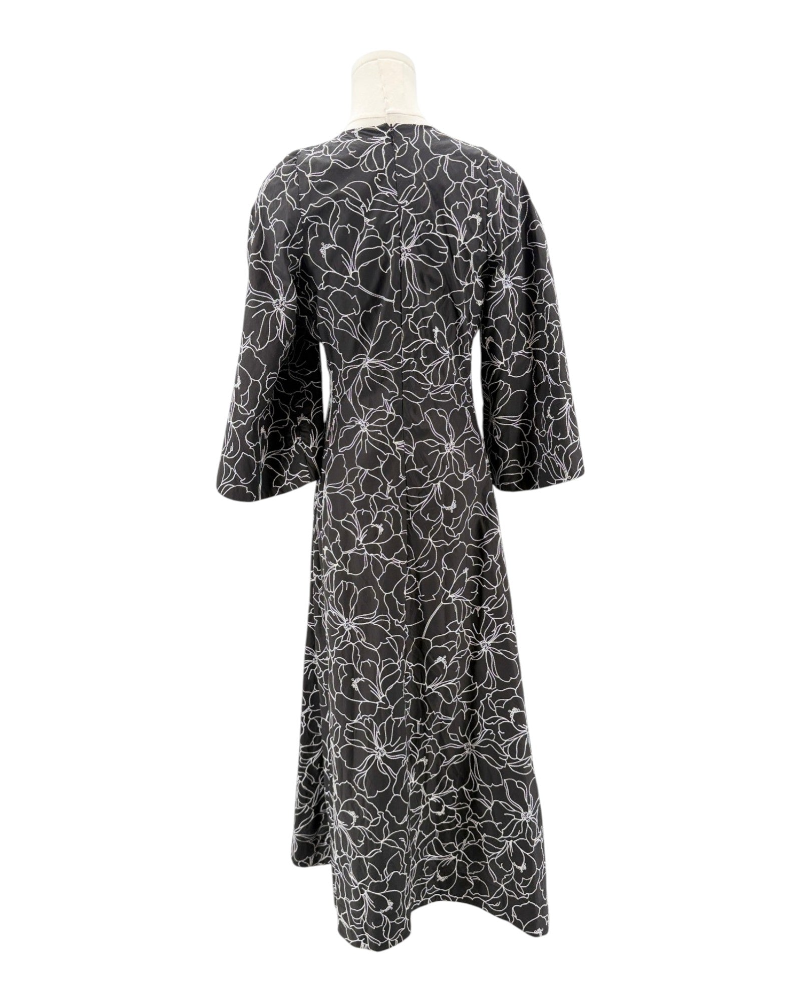 Black dress with white floral pattern on a mannequin against a white background