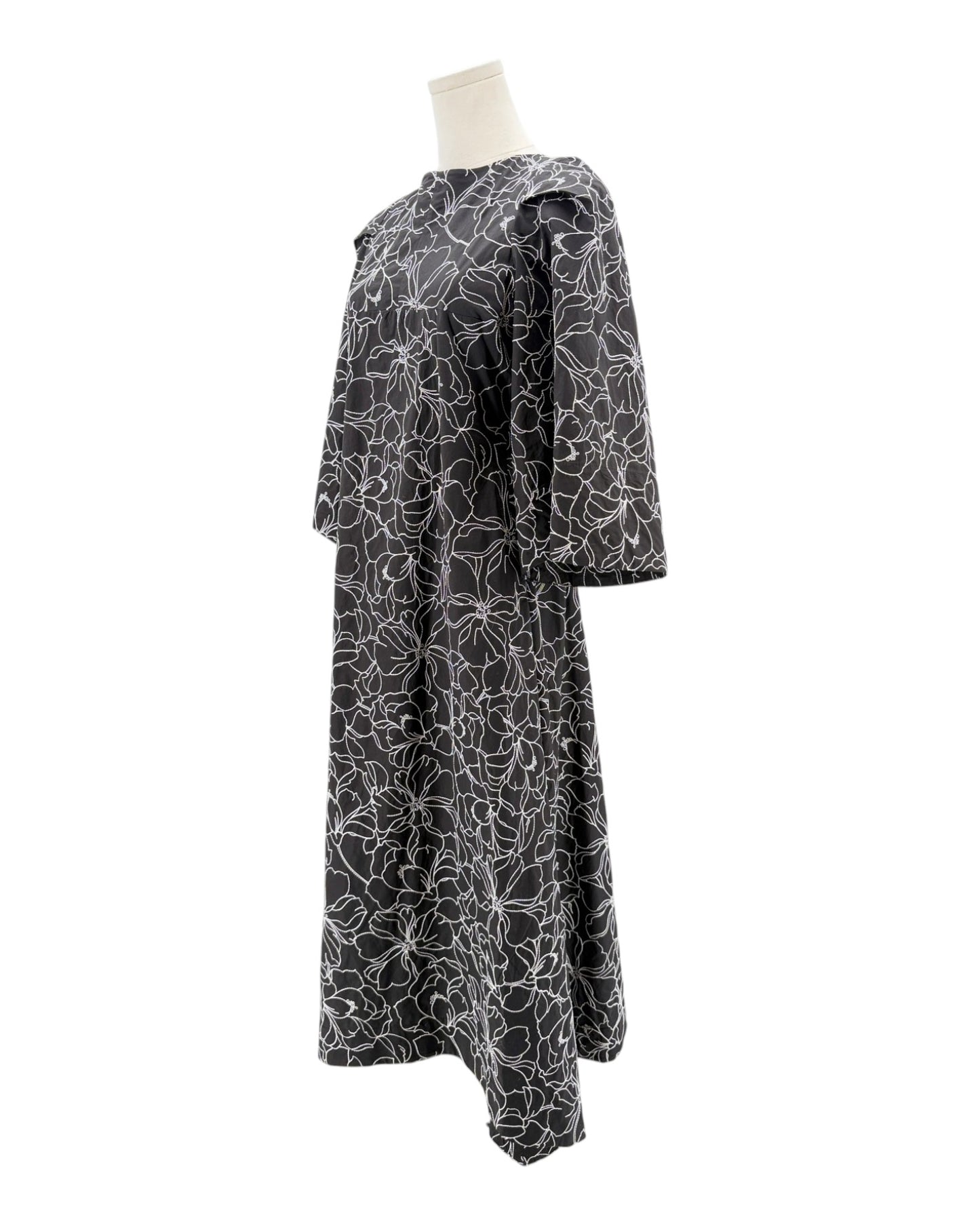 Black dress with white floral pattern on a mannequin against a white background
