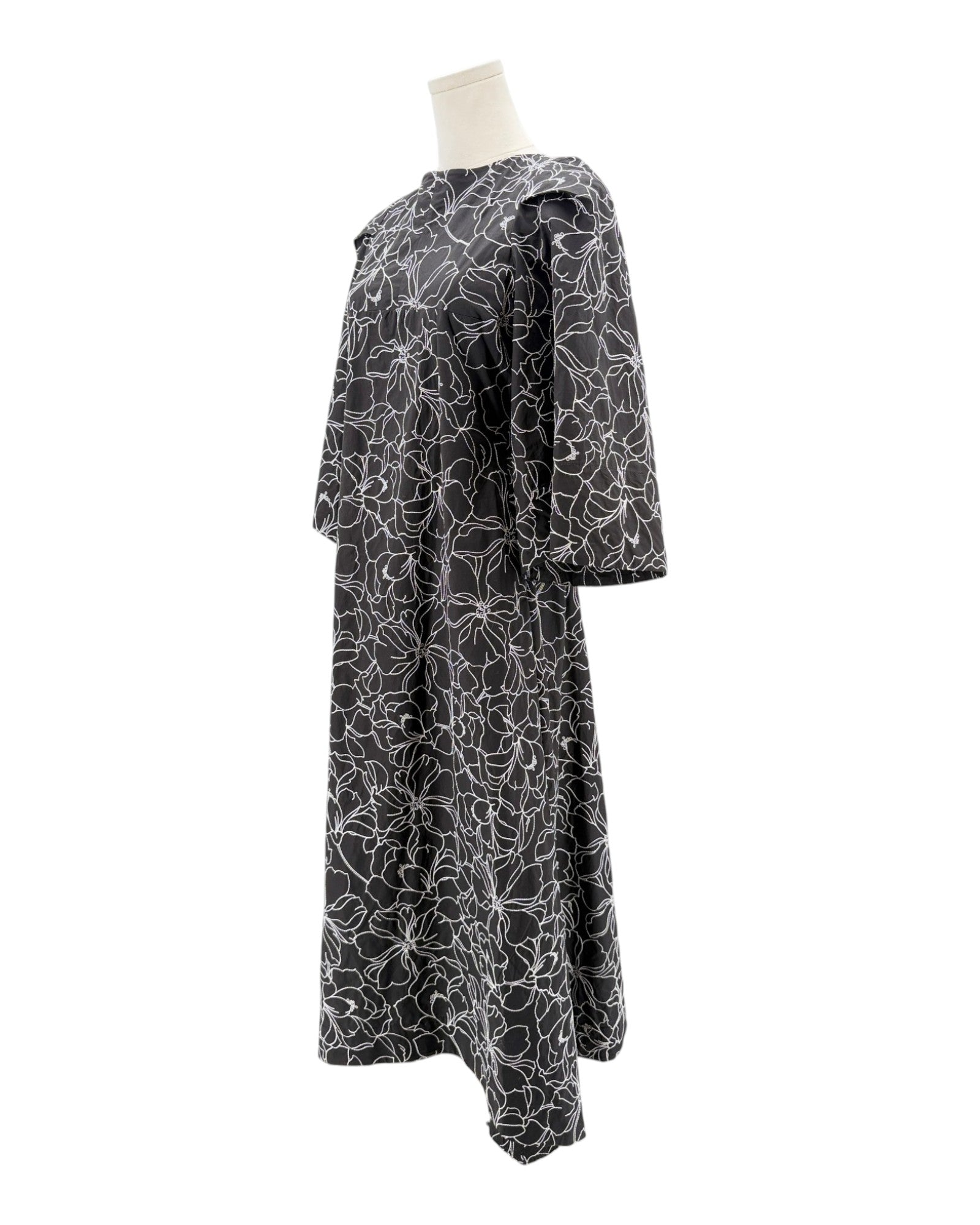 Black dress with white floral pattern on a mannequin against a white background
